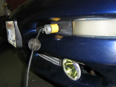 1995 Ford Probe - A blue car's front bumper is visible, a yellow fog light and a power cord plugged into a yellow connector on the bumper.