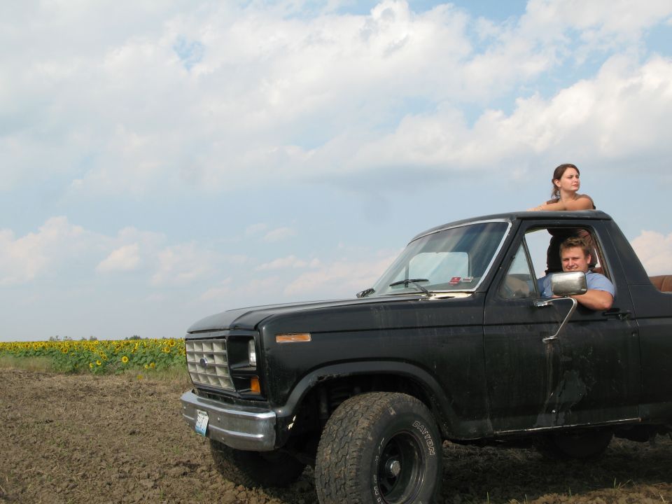 Black Ford Bronco with two people in a field of sunflowers