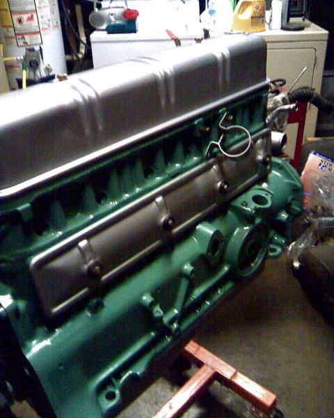1953 Ford Mainline - Close-up of a green engine block and silver valve cover, likely a vintage automotive part.