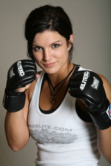 Woman in boxing gloves and white tank top with text "ELITEFC.COM" and "SUPERMOTORS"