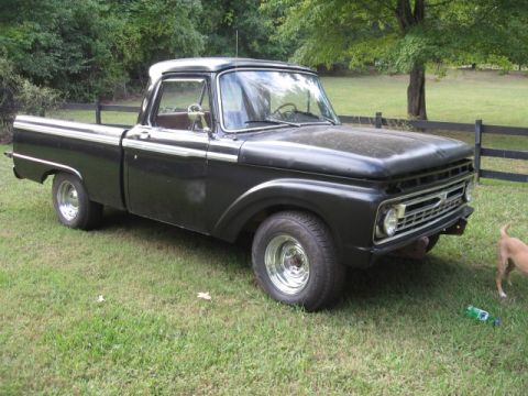 1966 Ford F-100 - This black 1966 Ford F-100 pickup truck is shown in a three-quarter front view, parked on a grassy lawn.