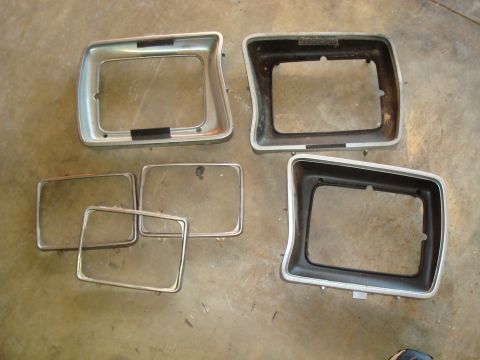 1995 Ford Bronco - Several headlight bezels and glass lenses are laid out on a textured floor.