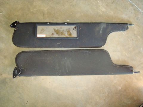 1995 Ford Bronco - Two black sun visors are displayed, one a vanity mirror with a small label. The parts appear to be for an older vehicle.