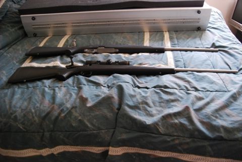 1991 Ford Bronco - Two long guns are placed on a patterned bedspread, with a piece of equipment in the background.
