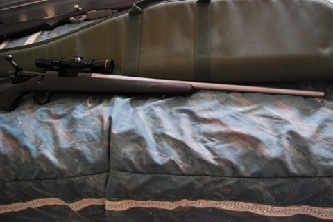 1991 Ford Bronco - A rifle with a scope and a green gun bag are displayed on a patterned blanket.