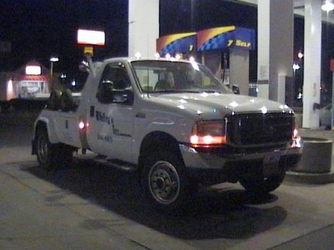 1990 Ford Bronco - Tow truck with 'Walling & Sons' text on the side is seen at a gas station.