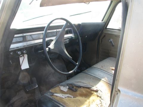 1971 International Travelall - The interior of a 1971 International Travelall shows a worn seat and dashboard with a large steering wheel.