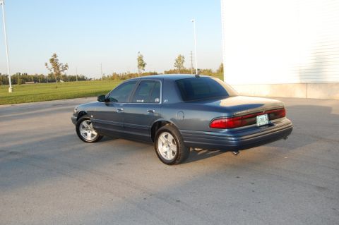 1985 Mercury Grand Marquis - Rear view of a blue sedan parked outdoors on a paved surface.