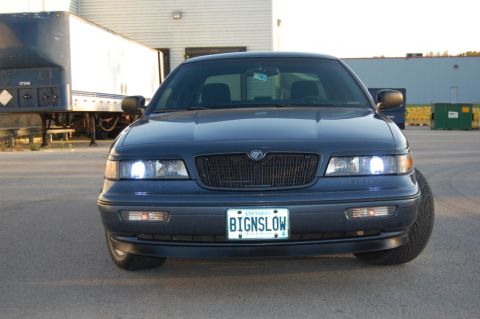 1985 Mercury Grand Marquis - This dark blue sedan features a distinctive black grille and a personalized Ontario license plate.