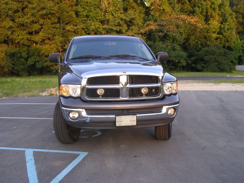 1989 Ford Bronco - This dark blue pickup truck is shown from the front, a prominent chrome grille and fog lights.
