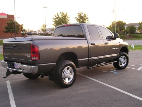 1989 Ford Bronco - This Dodge Ram pickup truck is parked in a lot with a tonneau cover on the bed.
