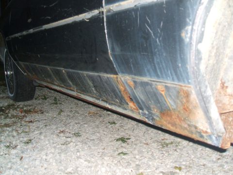 1982 Oldsmobile Cutlass - The lower body panel of a 1982 Oldsmobile Cutlass displays significant rust and wear, with a tire visible on the left.