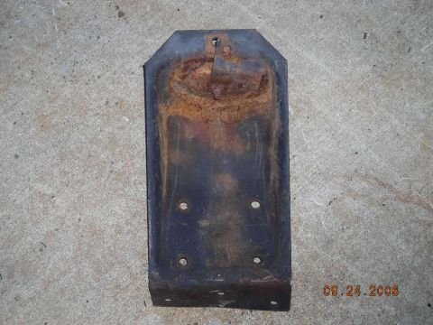 1993 Ford Bronco - A heavily rusted metal bracket, likely a vehicle part, lies on a concrete surface.