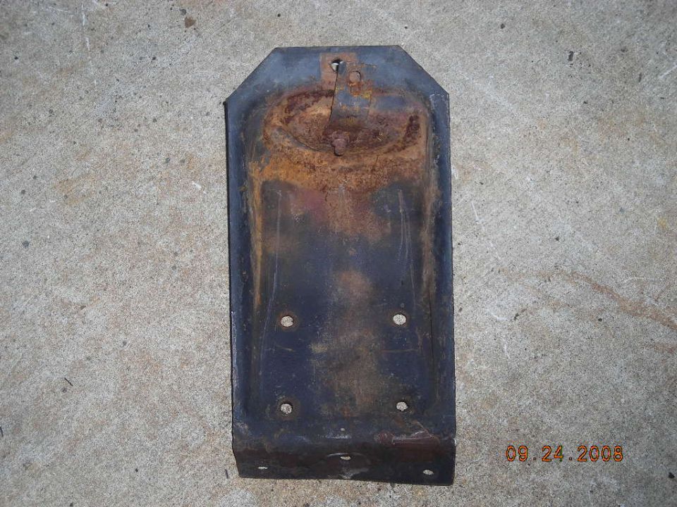 Rusted metal bracket with four mounting holes and a central raised section