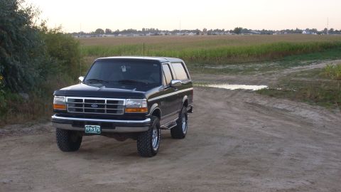1996 Ford Bronco - This black 1996 Ford Bronco is parked on a dirt road, with a cornfield in the background.