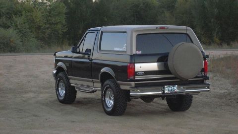 1996 Ford Bronco - This two-tone 1996 Ford Bronco is shown from a rear three-quarter view, parked on a dirt road.