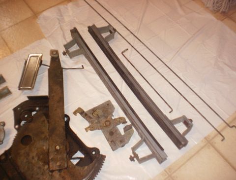 1986 Ford Bronco - Various window regulator components and rods are laid out on a white sheet.