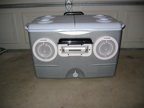 cooler with two white Alpine speakers and a car stereo installed
