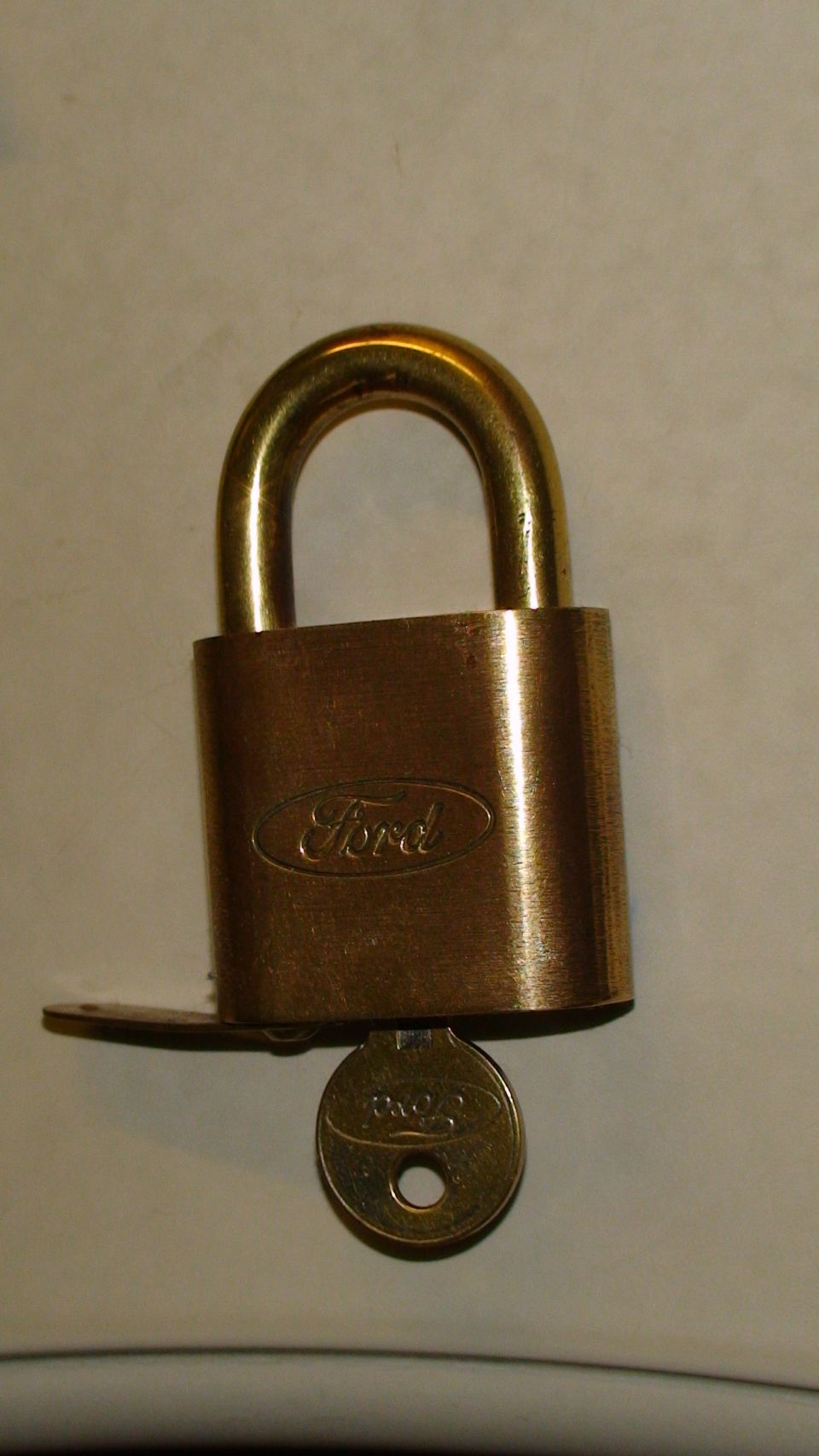Brass padlock with Ford logo and a key inserted