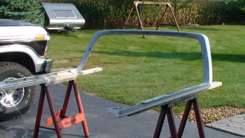 1979 Ford Bronco - A gray soft top frame for a Ford Bronco is shown on sawhorses, with a 1978 Ford truck visible to the left.