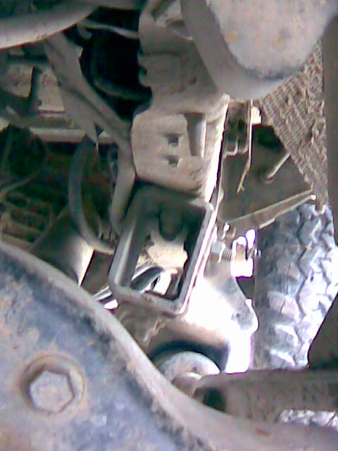 1989 Ford Bronco - Close-up view of a vehicle's undercarriage, showing mechanical parts and a tire.