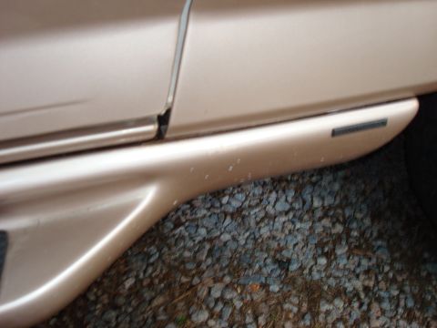 1992 Ford Bronco - Close-up of the side body panel and trim of a tan vehicle.