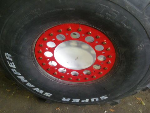 1979 Ford Bronco - This Super Swamper tire features a red beadlock ring and a silver inner rim, indicating a focus on off-road performance.