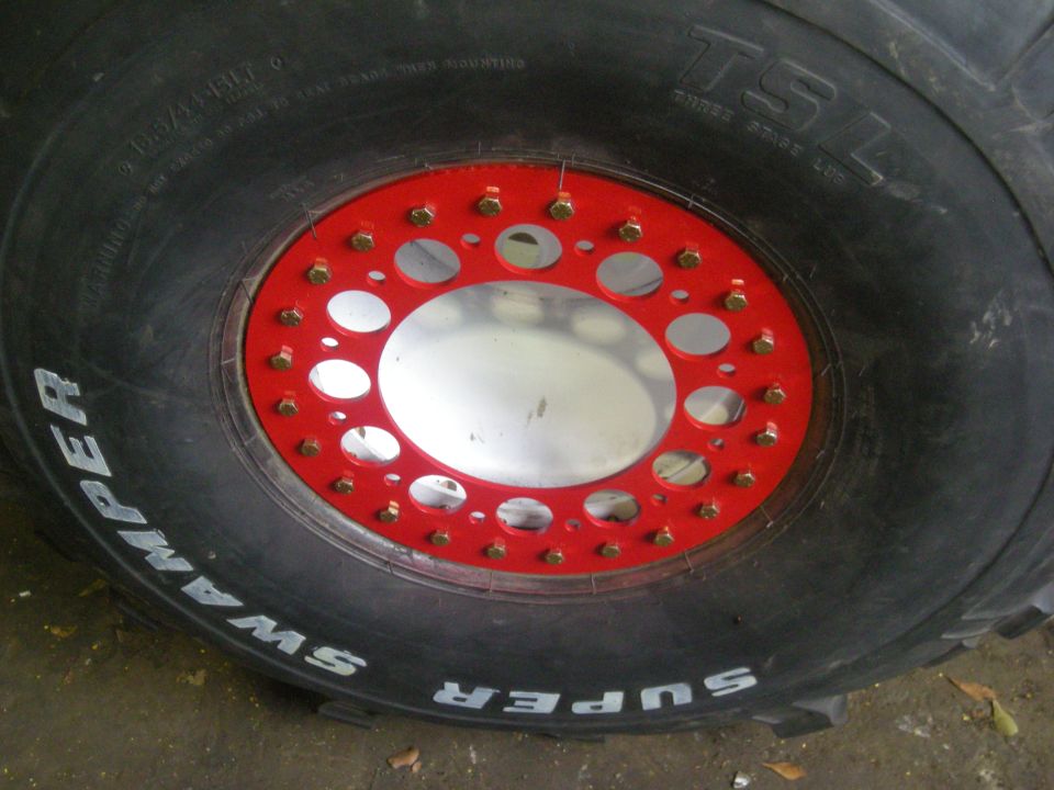 Close-up of a Super Swamper tire with a red beadlock and silver rim