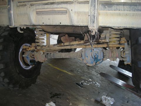 1979 Ford Bronco - The rear axle and suspension components of a heavily modified vehicle are visible, covered in dirt and grime.