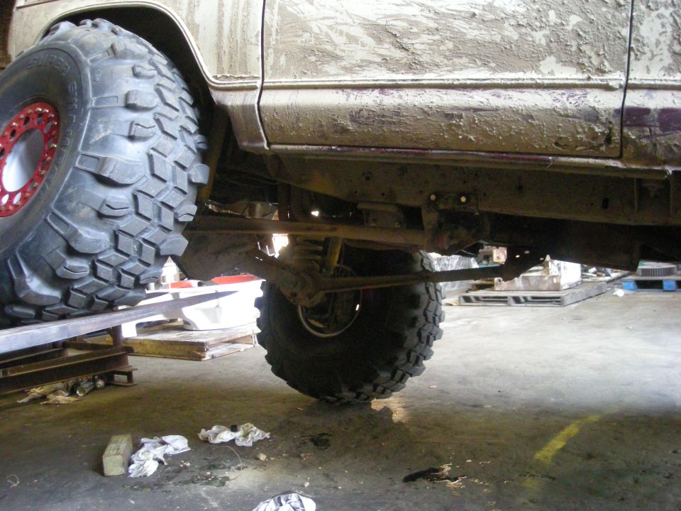 muddy off-road vehicle side view, showing large tires and suspension components