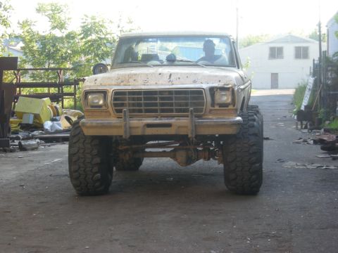 1979 Ford Bronco - This 1979 Ford Bronco is equipped with large off-road tires and appears to be in a workshop or junkyard setting.