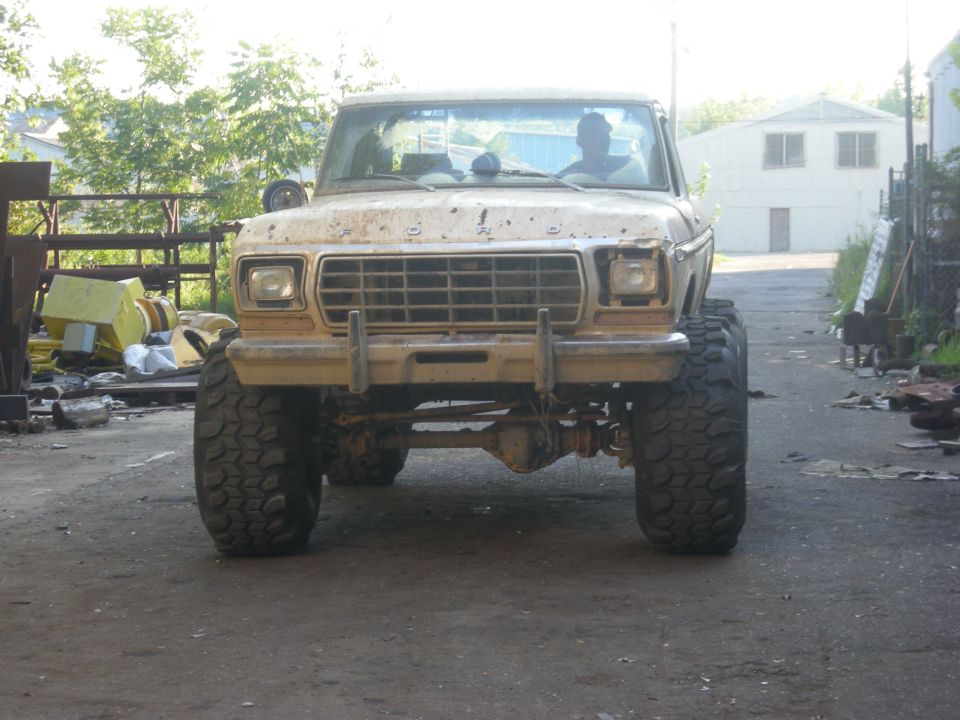 Tan 1979 Ford Bronco with large off-road tires, front view, dirty condition
