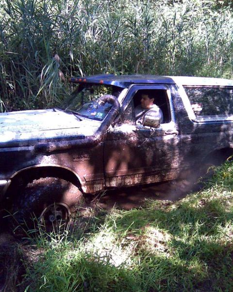 1989 Ford Bronco - This 1989 Ford Bronco appears to be stuck deep in mud and vegetation, with a snorkel visible.