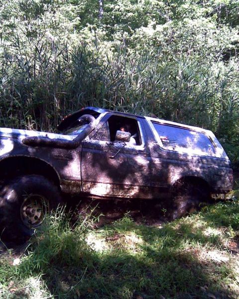 1989 Ford Bronco - 1989 Ford Bronco deep in mud off-road, with snorkel visible.