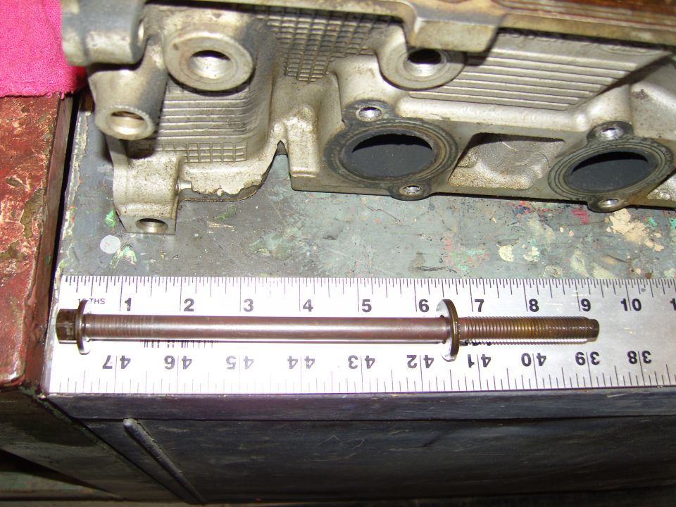 Engine cylinder head with a bolt and ruler measuring approximately 7 inches