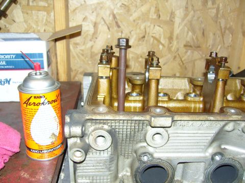 2007 Ford Mustang - Engine cylinder head with Kano Aerokroil can and other tools on a workbench.