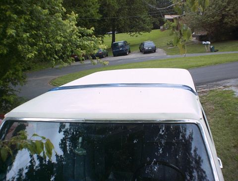 1986 Ford Bronco - The front view of a white 1986 Ford Bronco is captured, with other vehicles visible on the road behind it is the background.