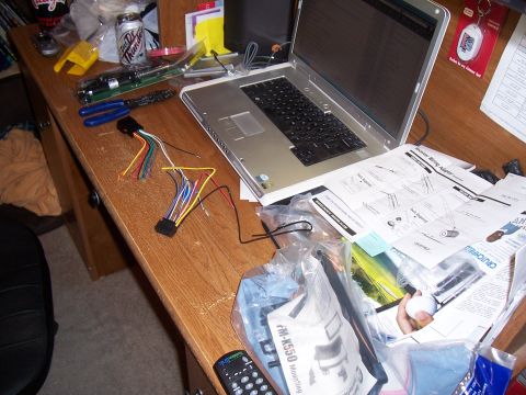 2003 Ford Ranger - A cluttered desk displays car stereo installation components, including a wiring harness, laptop, and various manuals.