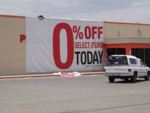 2000 Mercury Grand Marquis - A white van with a camper shell is parked in front of a building displaying a large "0% OFF SELECT ITEMS TODAY" banner.