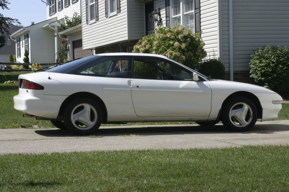 1997 Ford Probe parked on a driveway in front of a suburban house