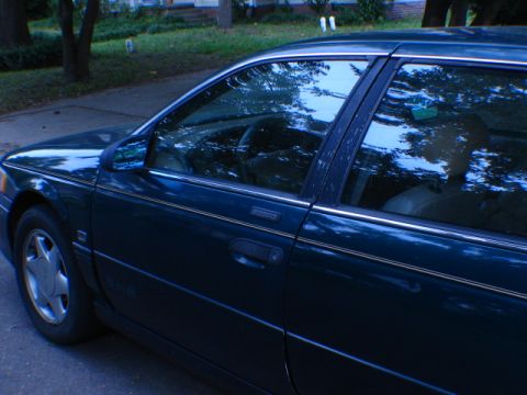 1993 Ford Taurus - Side view of a dark green 1993 Ford Taurus sedan parked on a street.