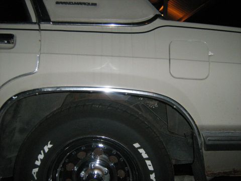 1988 Mercury Grand Marquis - Rear quarter panel detail of a white sedan, showing chrome trim and the 'GRANDMARQUIS' nameplate.