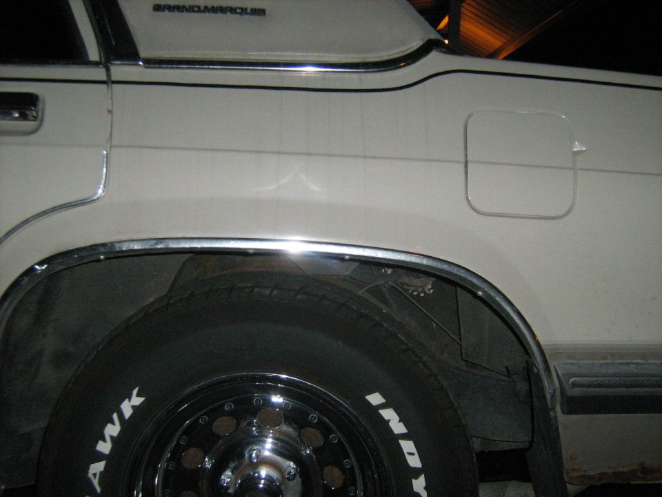 White sedan rear quarter panel with chrome trim and 'GRANDMARQUIS' text