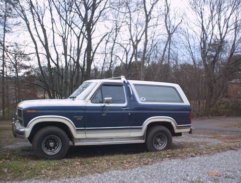1986 Ford Bronco - Side view of a blue and white 1986 Ford Bronco.