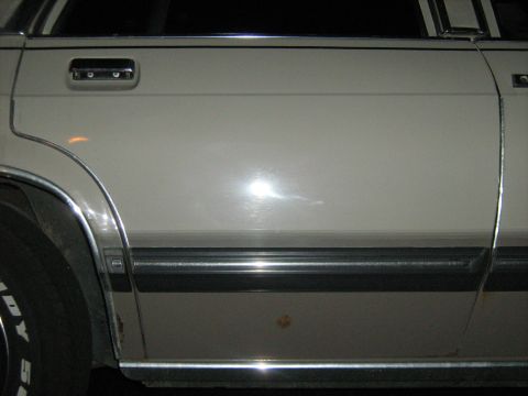 1988 Mercury Grand Marquis - Close-up of the side of a 1988 Mercury Grand Marquis, showing the door panel and wheel.