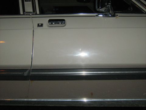 1988 Mercury Grand Marquis - Close-up of a car's side panel, highlighting the door handle and trim details.