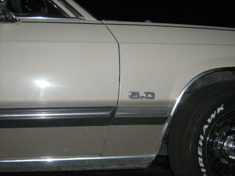 1988 Mercury Grand Marquis - A close-up view of a car's fender shows a "5.0" emblem and a Firehawk tire.