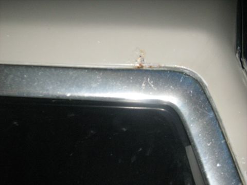 1988 Mercury Grand Marquis - Rust is visible on the upper corner of a car's body panel, adjacent to a chrome trim piece.