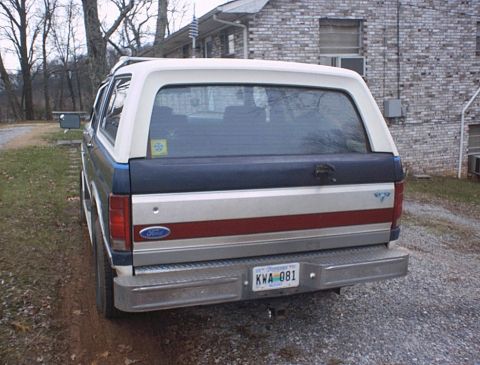 1986 Ford Bronco - The rear of a 1986 Ford Bronco is shown parked next to a brick building.