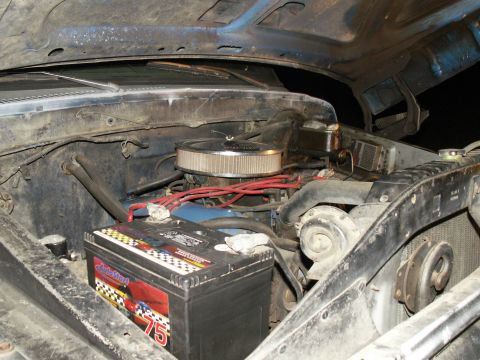 1977 Ford F-250 - The engine bay of a 1977 Ford F-250 shows a blue engine block, an aftermarket air filter, and a prominent battery.